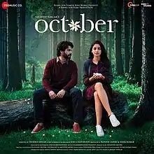 The soundtrck album cover features Varun Dhawan and Banita Sandhu seated on a wood log lying in a jungle. They appear wearing winter-seasoned clothes depicting the month of October. The album title appears at top.