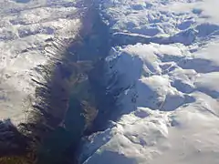 Aerial view, looking south.  The fjord is on the bottom of the picture, then the town, then the lake Sandvinvatnet at the top.  The snow-covered mountains surround the town.