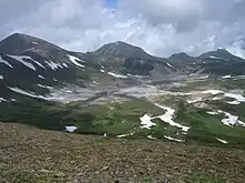 Flat valley or caldera with patches of snow.