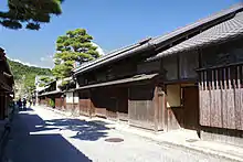 Two storied wooden houses next lining a street.