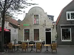 Small gable to gable building in yellow brick with details in red stone, dated 1722, on the island of Terschelling in the Netherlands