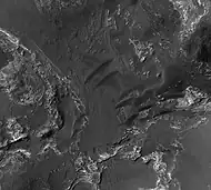 Orson Welles Crater, as seen by HiRISE.  Layered, light-toned rocks seem to be under a dark mantling material.  Layers may be sandstone, volcanic ash, or lakebed deposits.