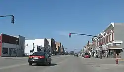 A car stopped at a traffic signal in the downtown area of a small town.