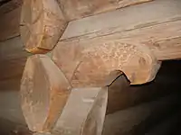 Ornamental woodcarving in the shape of an eagle's head on a projecting log in the wall of the loft from Ose at Norsk Folkemuseum.