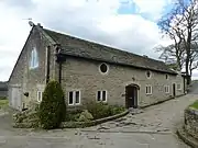 A long stone building with round windows and a former wagon arch