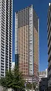 Ground-level view of a rectangular, window-dotted high-rise; the facades are tri-colored with white, beige and gray areas