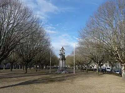 2 rows of trees aligned on either side of a wide driveway, with the war memorial in the center.