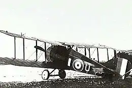 Rear three-quarter view of military biplane on landing ground