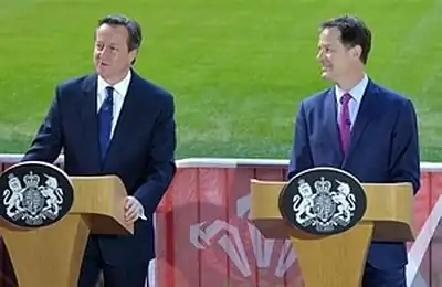 Colour photograph of David Cameron and Nick Clegg standing behind podiums in February 2015