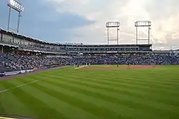 A green baseball field surrounded by navy blue seats with three light towers high above