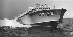 a powerboat speeds across the water, riding high so the hull is exposed. "PT 32" is painted on the hull in large white letters.