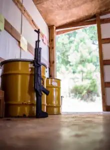 Rifle leaning against barrel on gun range.