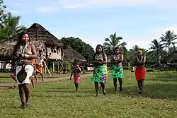 Four women, in colorful skirts, and a child outdoors