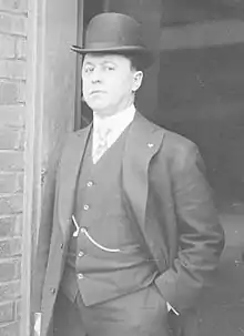 A man in a dark suit and hat