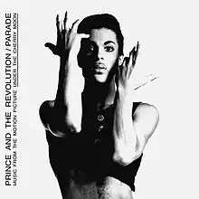 A black a white photo of a man with a black tank top and his arms posed in a theatrical way with the words "PRINCE AND THE REVOLUTION/ PARADE"