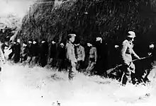 Soldiers putting blindfolded people up against a wall