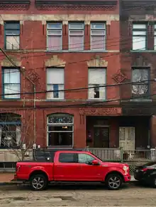 A photo of a red brick rowhouse with three stories.