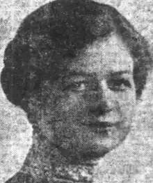 A young white woman with dark hair parted on the side and dressed into an updo, wearing a high lace collar