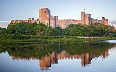 exterior of a large medieval castle with water in foreground