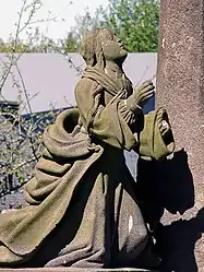 Mary Magdalene kneels in prayer at the foot of the cross