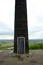 A door in a stone column, covered with a metal grate