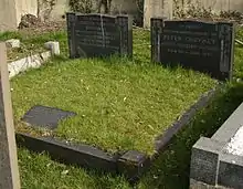 Two polished, black granite headstones surrounded by other gravestones