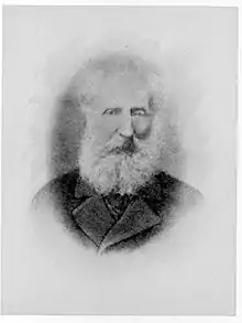 Black and white head and shoulders portrait of a man with a large white beard