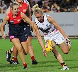 Phillips staring down at and ready to pick up the ball on the ground while being chased