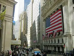 A large flag is stretched over Roman style columns on the front of a large building.