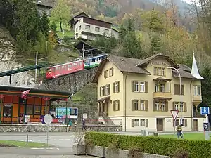 Train ascends incline behind four-story building with gambel roof