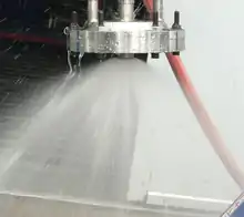 A pintle injector is shown during a cold flow test. Both flow paths are active.