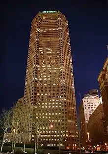  A tall beige building with the word "Mellon" in glowing green letters on the top.