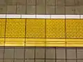 Tactile pavings installed on a platform at a Japanese train station. Horizontal tactile paving at the bottom indicates the 'inner' side, away from the rail tracks.