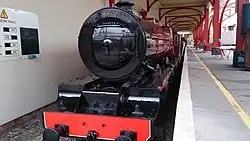 Maroon coloured miniature locomotive sits in the station