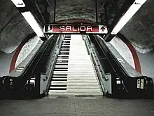 A staircase decorated as if each step was the key of a piano. It is located between two escalators.