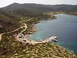 Photo of a tree and scrub-covered island taken from a hill which overlooks a pier.