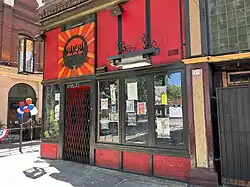 Street view of the red storefront bar, with picnic tables in front