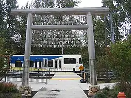 Timber gateway and a waiting train.  Facsimiles of historical newspaper headlines are at the base of the wooden poles.