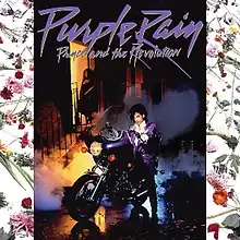 Prince in a purple motorcycle with a person standing in front of an building behind him with the door open. Various flowers appear in the sides.