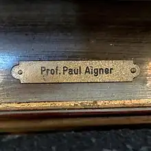 engraved plate on a wooden picture frame, stating Professor Paul Aigner