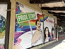 Photograph of a building exterior featuring paintings of Freddie Mercury, Cher, and Selena, as well as the text "Pride Strip" and "Mr. Flamingo"