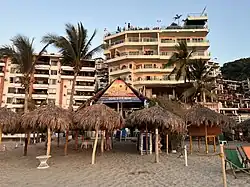 Photograph of a beach club in the foreground and multi-level buildings in the background