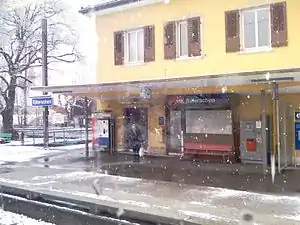 Snow falls on a two-story building with gabled roof