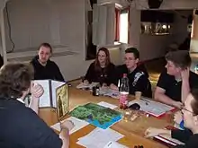 Image 23A group playing a tabletop RPG. The GM is at left using a cardboard screen to hide dice rolls from the players. (from Role-playing game)