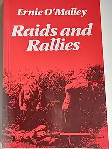 "Colour photograph of the front cover of Raids and Rallies by Ernie O'Malley; cover shows three men in paramilitary clothing, two of whom are firing weapons from behind a hedge as their officer looks on"