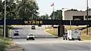 A railroad bridge crosses over a four-lane highway, with the bridge painted "Welcome to Wynne, The City with a Smile"