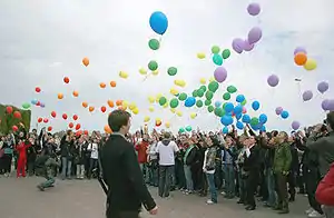 Large group of people releasing multicolored balloons