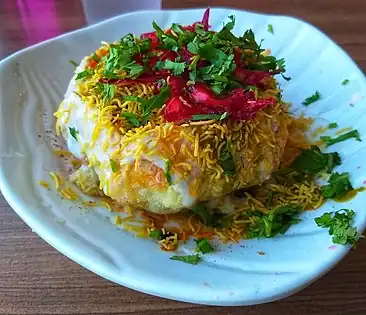 Raj Kachori with spiced green gram lentils, chickpeas, served with yogurt, chutnies and sev on top.