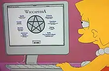 Lisa Simpson seated at a desk, facing a computer monitor, performing online research.