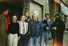 A group of seven people stand near the entrance of a building.